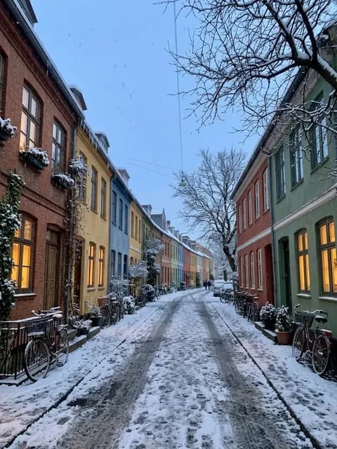 A street before and after the edit "Make it winter": the same buildings under snow at dusk